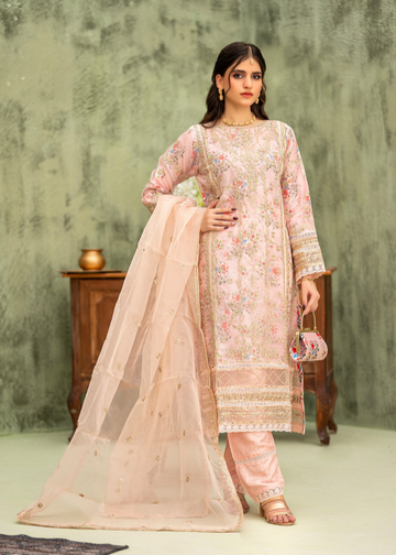 Woman wearing a traditional outfit with a floral top and beige dupatta against a textured wall.