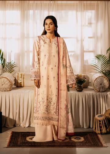 Woman in a traditional embroidered outfit standing in a decorated room with plants and furniture.