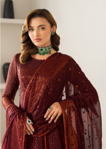 Woman wearing a maroon saree with intricate designs indoors.