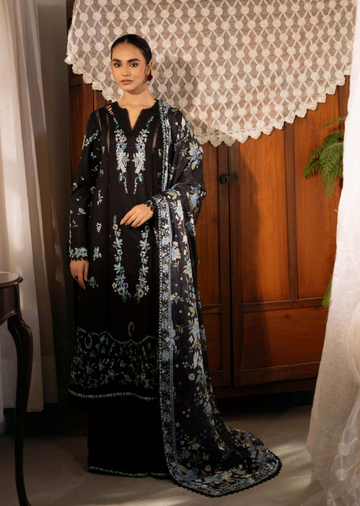 Woman wearing a black embroidered dress standing in a room with wooden paneling and lace curtains.