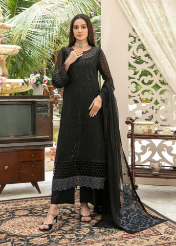 Woman in a black traditional outfit standing in a decorated room with a fountain and decorative wall.