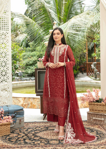 Woman in a red embroidered outfit standing in a decorative outdoor setting with plants and furniture.
