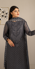 Woman wearing a dark gray embroidered traditional outfit with a plain background