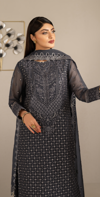Woman wearing a dark gray embroidered traditional outfit with a plain background