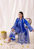 Woman in a blue and white patterned outfit sitting on a chair with a white background