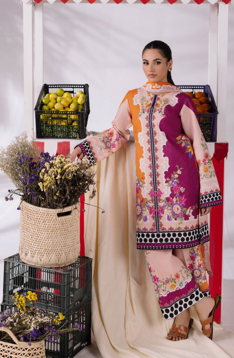 Woman in a colorful traditional outfit standing next to fruit crates and flowers.
