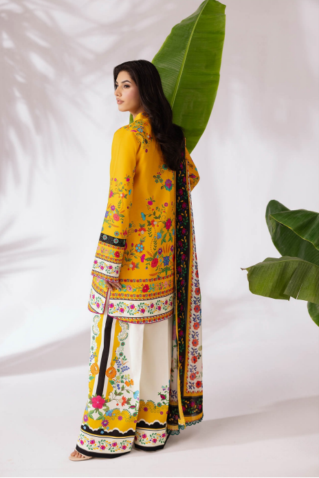 Woman in a yellow and floral traditional outfit with green leaves in the background