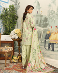 Woman in a light green traditional outfit with floral patterns in an ornate setting.