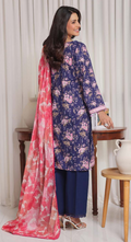 Woman wearing a blue floral dress with a pink dupatta in a room setting.