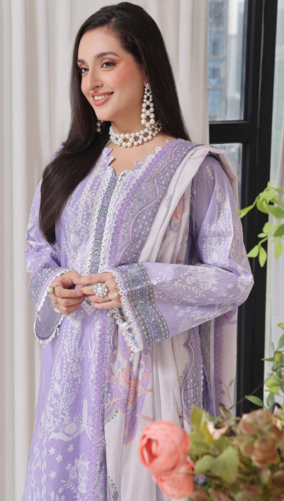 Woman in a light purple traditional outfit with white dupatta, standing indoors.