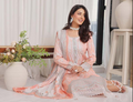 Woman in a light pink traditional outfit sitting indoors with decorative elements.