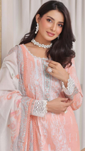 Woman wearing a peach and white embroidered traditional outfit with jewelry.