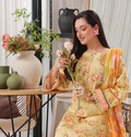 Woman in a floral dress holding flowers in a home setting with decor elements.