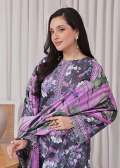Woman wearing a floral dress with a purple and green pattern in a room with plants and furniture.