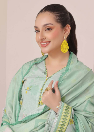 Woman wearing a light green traditional outfit with floral patterns indoors.