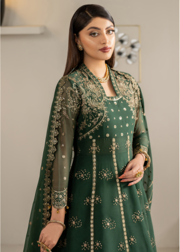 Woman wearing a green embroidered traditional outfit with gold details.