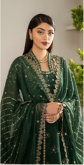 Woman wearing a green embroidered traditional outfit with a neutral background