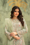 Woman wearing a light green embroidered outfit against a blurred natural background