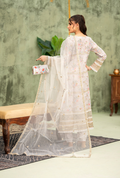 Woman in a white traditional outfit with a sheer dupatta, holding a clutch, against a green wall.