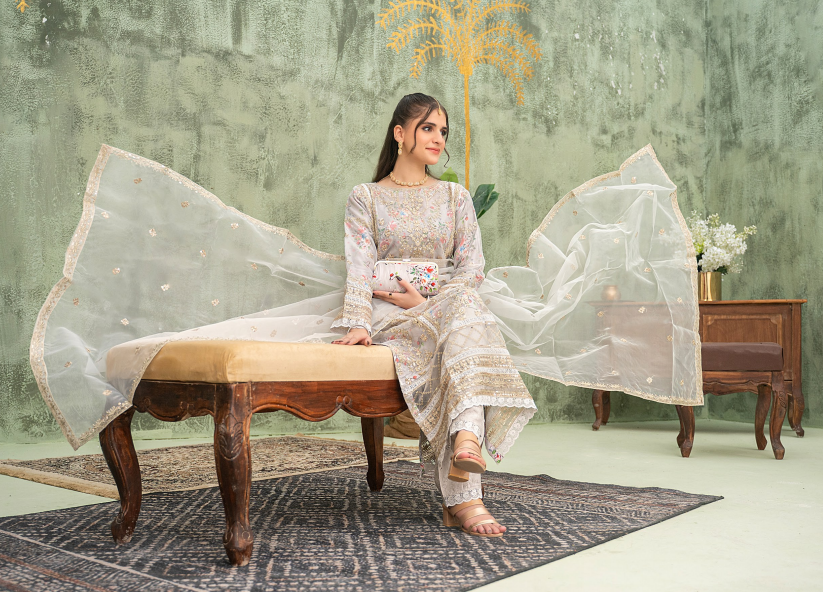 Woman in a traditional outfit sitting on a wooden bench with a decorative background