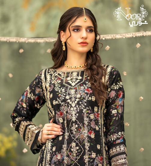 Woman wearing a black embroidered traditional outfit with jewelry against a green background