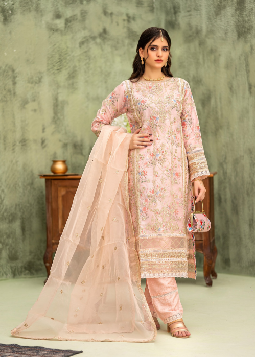 Woman wearing a traditional outfit with a floral top and beige dupatta against a textured wall.