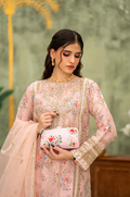 Woman in a pink traditional outfit holding a matching handbag against a blurred background