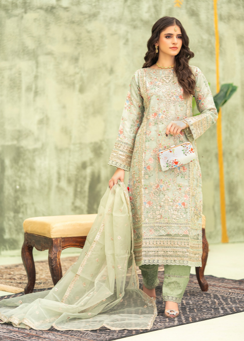 Woman in a light green embroidered outfit with a sheer dupatta, standing against a neutral background.