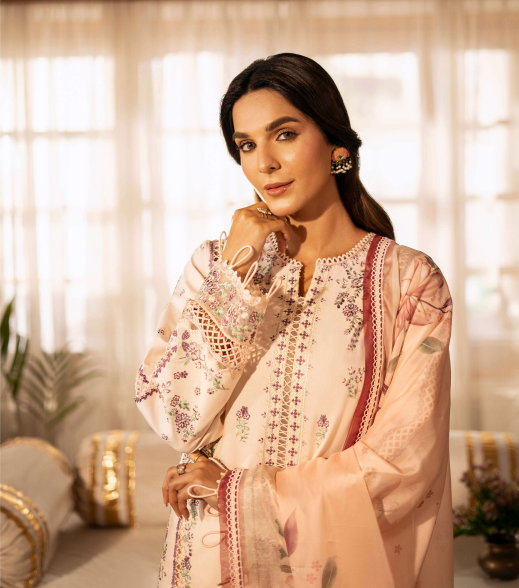 Woman in a traditional outfit with floral patterns in a softly lit room.