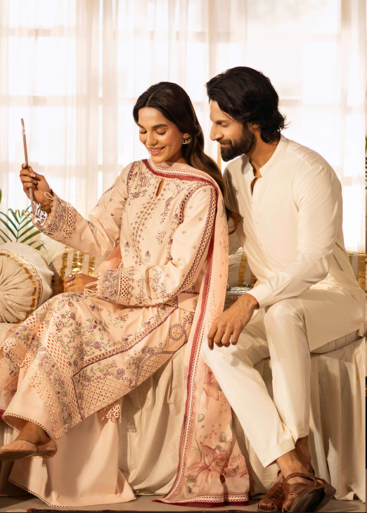 Man and woman in traditional attire sitting together, holding a phone.