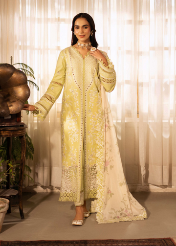 Woman in a light yellow embroidered traditional outfit standing in a softly lit room.