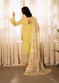 Woman in a light green traditional outfit with a white dupatta in a softly lit room.