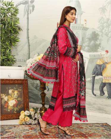 Woman in a pink traditional outfit with a patterned dupatta in a decorated room.
