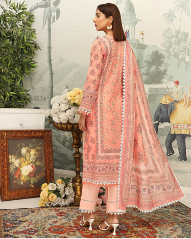 Woman in a pink embroidered traditional outfit standing in a decorated room with floral arrangements and a painting.