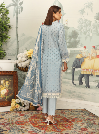 Woman in a light blue embroidered outfit standing in a decorated room with a painting and decorative elements.