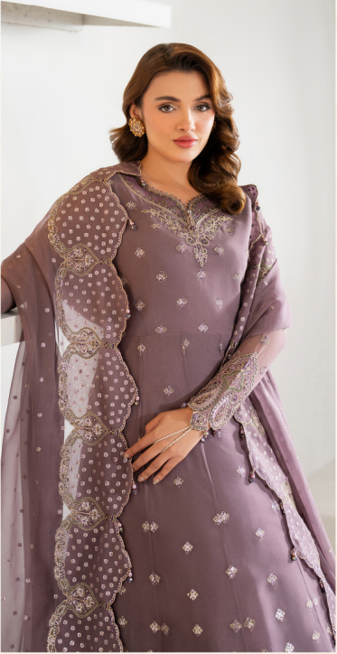 Woman wearing a mauve embroidered traditional outfit with a white background