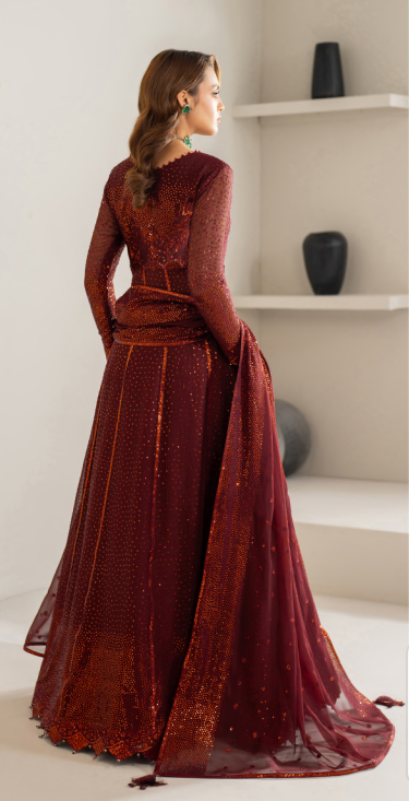 Woman in a burgundy evening gown standing in a minimalistic room.