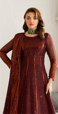Woman wearing a maroon dress with intricate patterns and a matching jacket against a plain background
