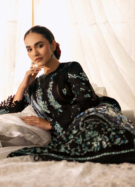 Woman wearing a black and white patterned dress sitting on a bed.