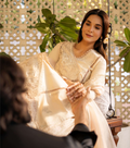 Woman in a white saree sitting on a swing with a decorative background
