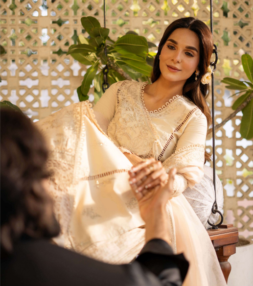 Woman in a white saree sitting on a swing with a decorative background