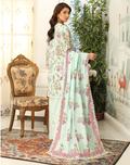 Woman in a floral dress standing in a decorated room with a chair and plants.