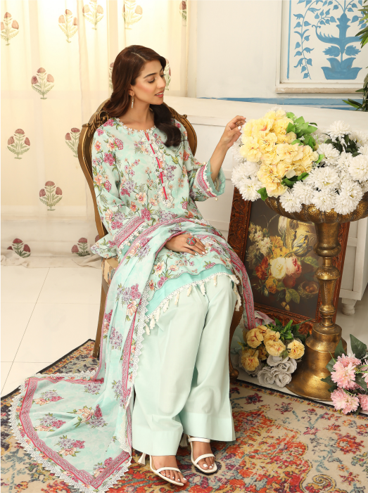 Woman in a floral dress sitting on a decorative chair with flowers and a painting in the background
