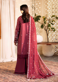 Woman wearing a maroon traditional outfit with a matching dupatta in a decorated room.