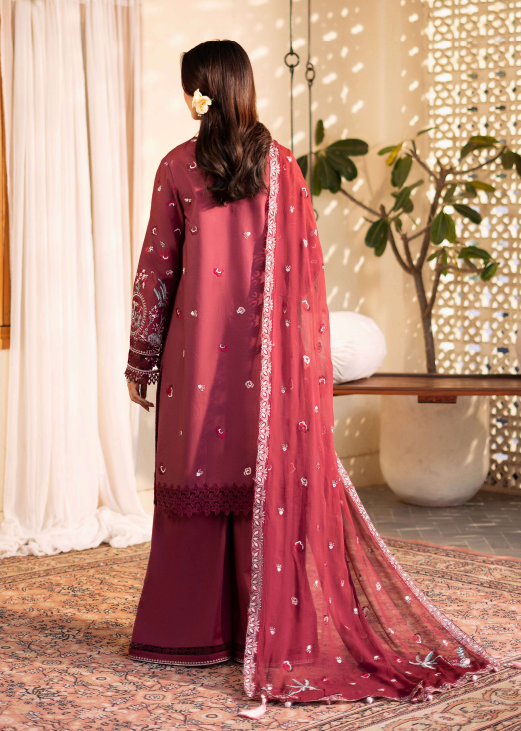 Woman wearing a maroon traditional outfit with a matching dupatta in a decorated room.