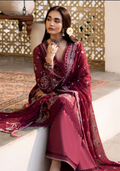 Woman in a burgundy embroidered traditional outfit sitting on a white surface.