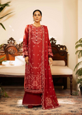 Woman wearing a red embroidered traditional outfit in a decorated room.
