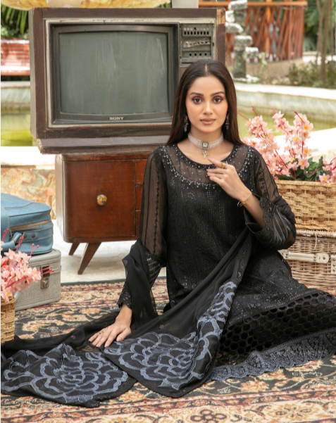 Woman in a black traditional outfit with a vintage television set in the background