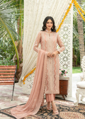 Woman in a pink traditional outfit standing in a decorated outdoor setting with palm trees.