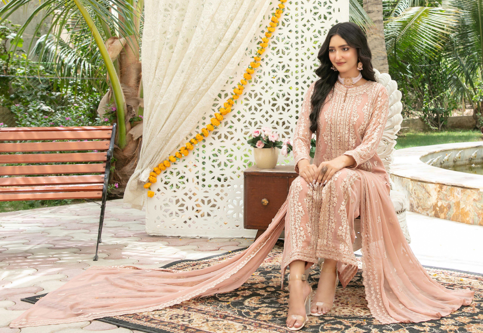 Woman in a peach traditional outfit sitting outdoors with decorative elements.